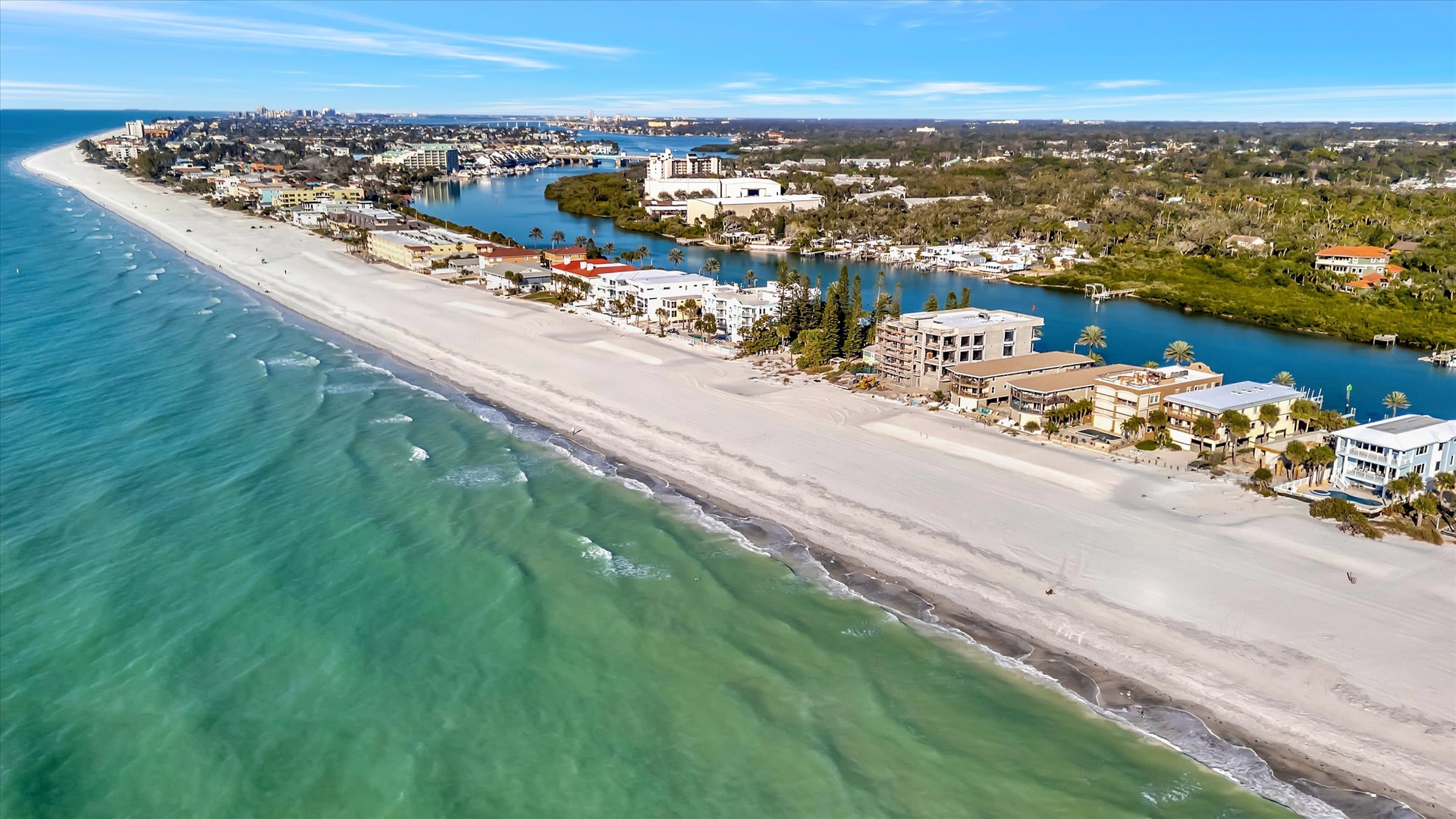 An aerial view captures the stunning coastal location, with pristine white sand beaches stretching along turquoise Gulf waters and a scenic inland waterway winding through the neighborhood.