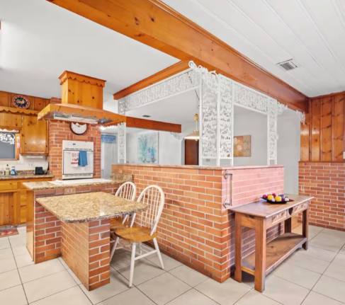 Warm brick accents and natural wood beams create a cozy, inviting kitchen and dining space where you can gather for home-cooked meals and make vacation memories together.
