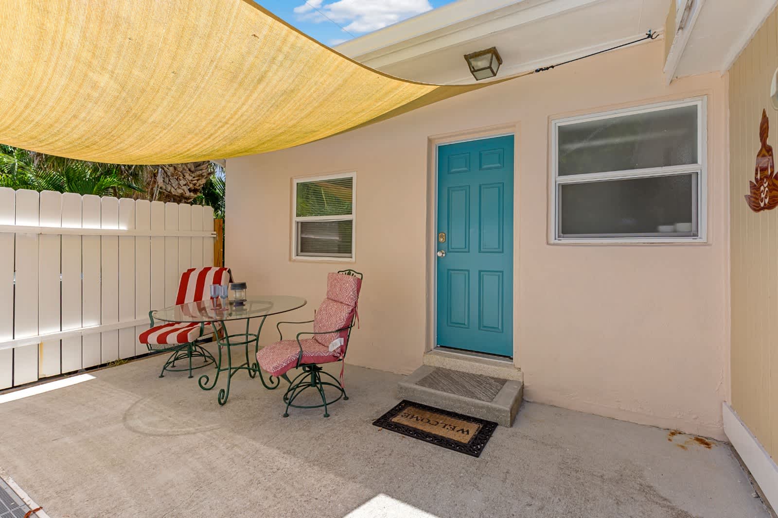 A bright turquoise door welcomes you to your private retreat, where a shaded patio offers a cozy spot to sip morning coffee or unwind after exploring the area.