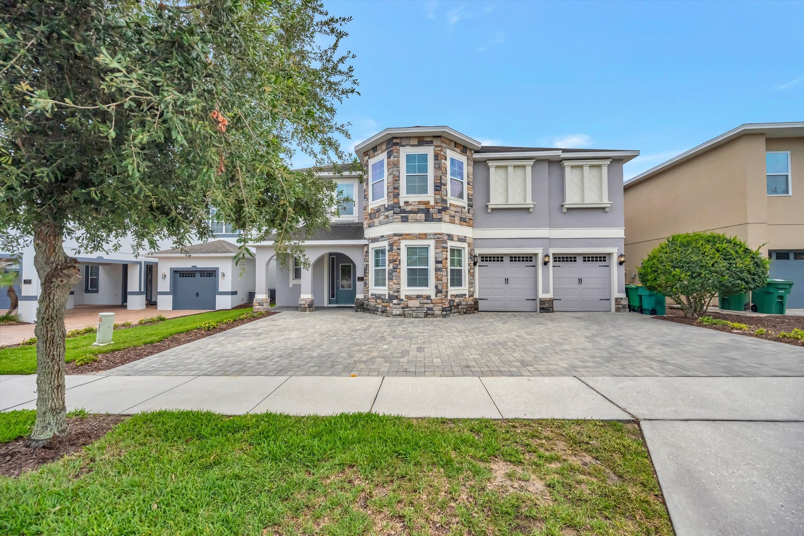 This inviting two-story home features stone accents and a spacious paver driveway, welcoming you to your comfortable vacation retreat in a well-maintained neighborhood.