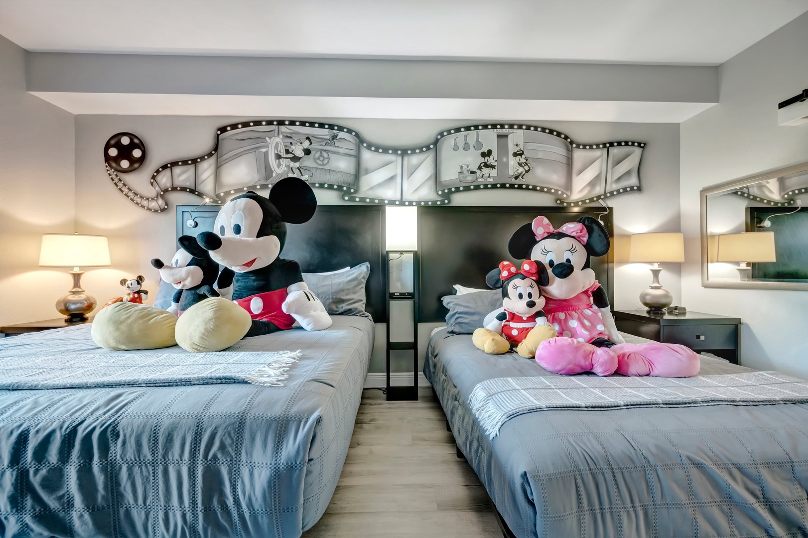 Step into your magical themed bedroom where whimsical film strip details frame twin beds dressed in soft blue linens. Perfect for families, this charming space brings playful Disney touches to your vacation stay.