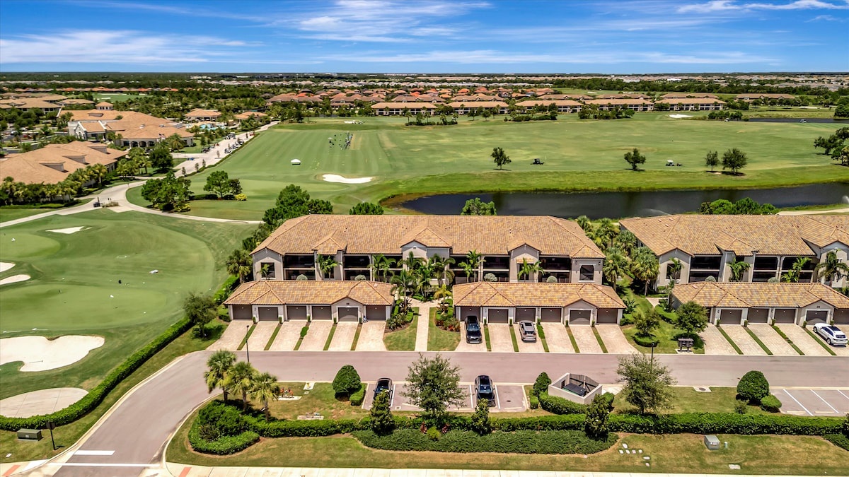 Aerial view of townhome-style vacation rental units overlooking a pristine golf course with water features and sand traps, set within a gated resort community.