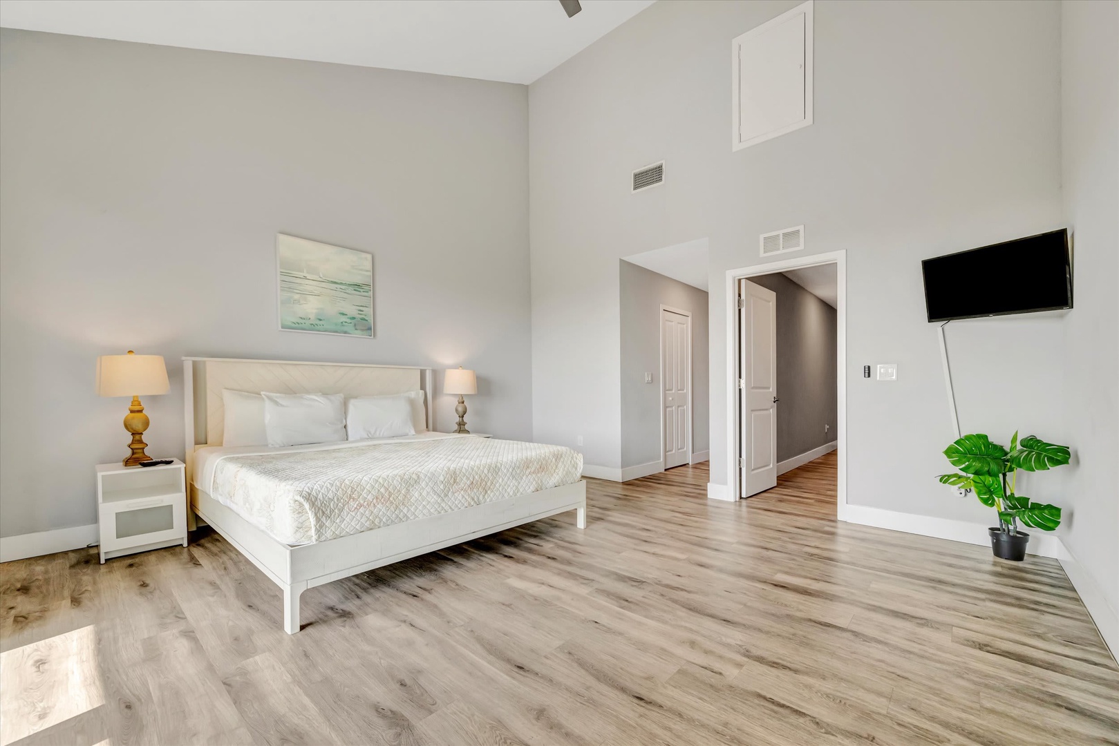 Step into your serene retreat with soaring vaulted ceilings and warm wood-style floors. Sink into the plush white bedding after a day of adventure, and unwind in the spacious, light-filled bedroom designed for your complete relaxation.