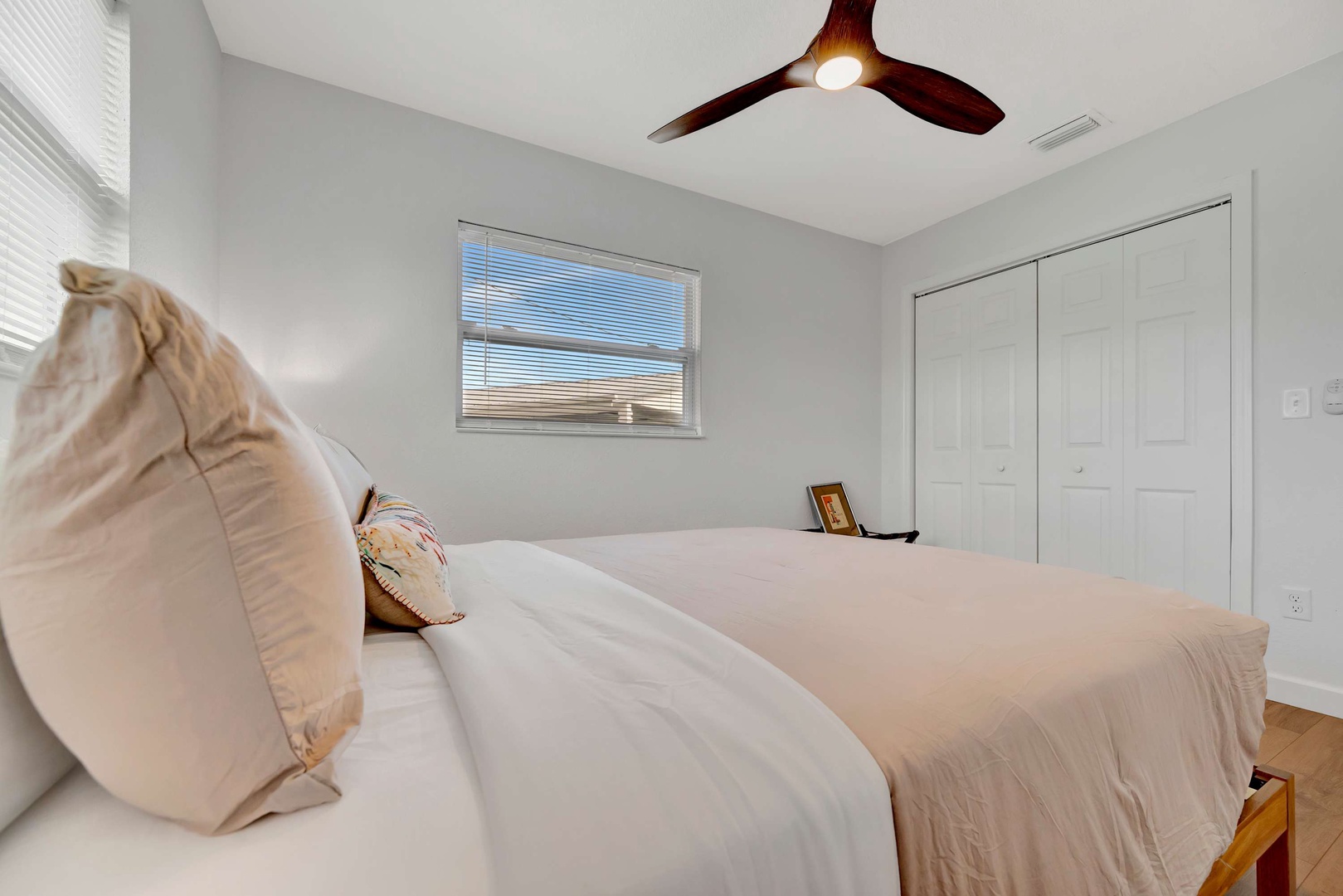 Unwind in your peaceful retreat with plush bedding, a gentle ceiling fan, and calming natural light flowing through the window.