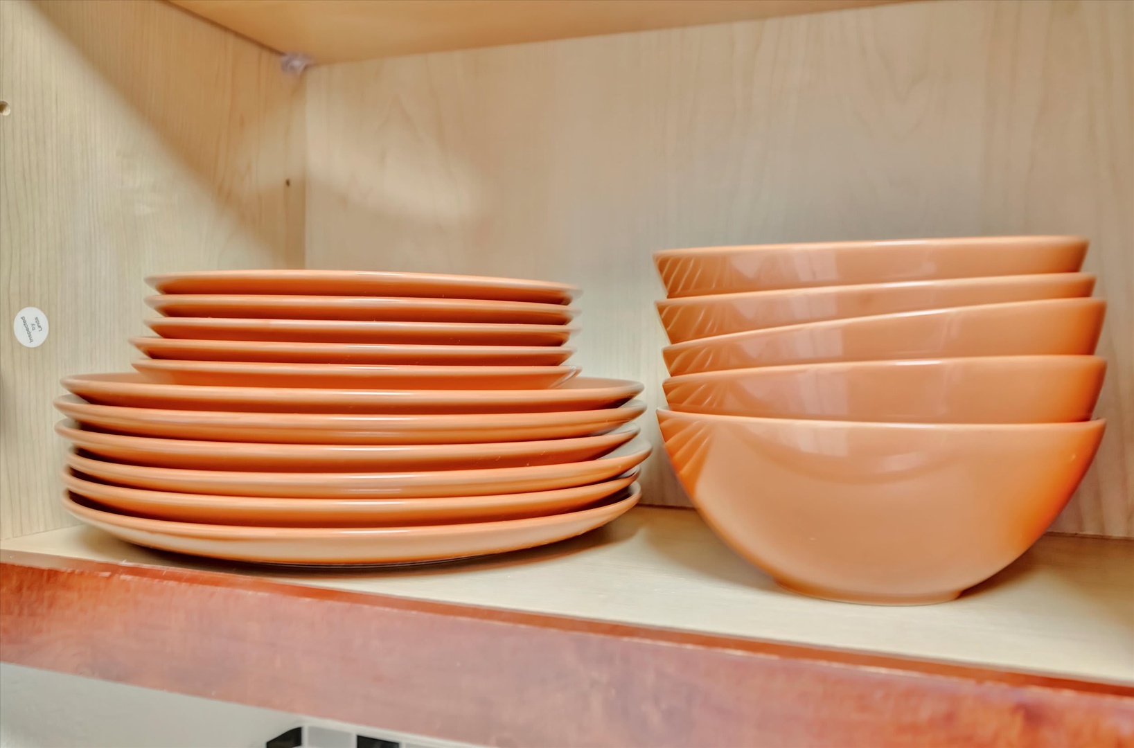 Your kitchen is thoughtfully stocked with cheerful peach-toned dishes and bowls, ready for cozy home-cooked meals or easy morning breakfasts during your stay.