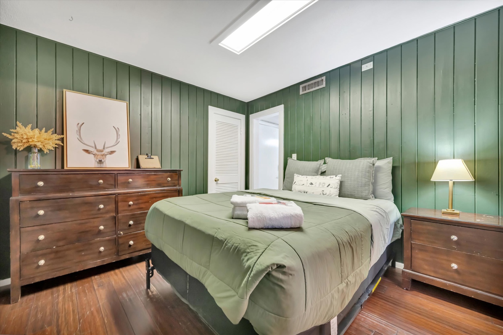 Step into your peaceful retreat, where sage-green walls and warm wood floors create a restful sanctuary. Sink into the plush bed with fresh towels awaiting, then unwind by soft lamplight in this thoughtfully designed, calming space.