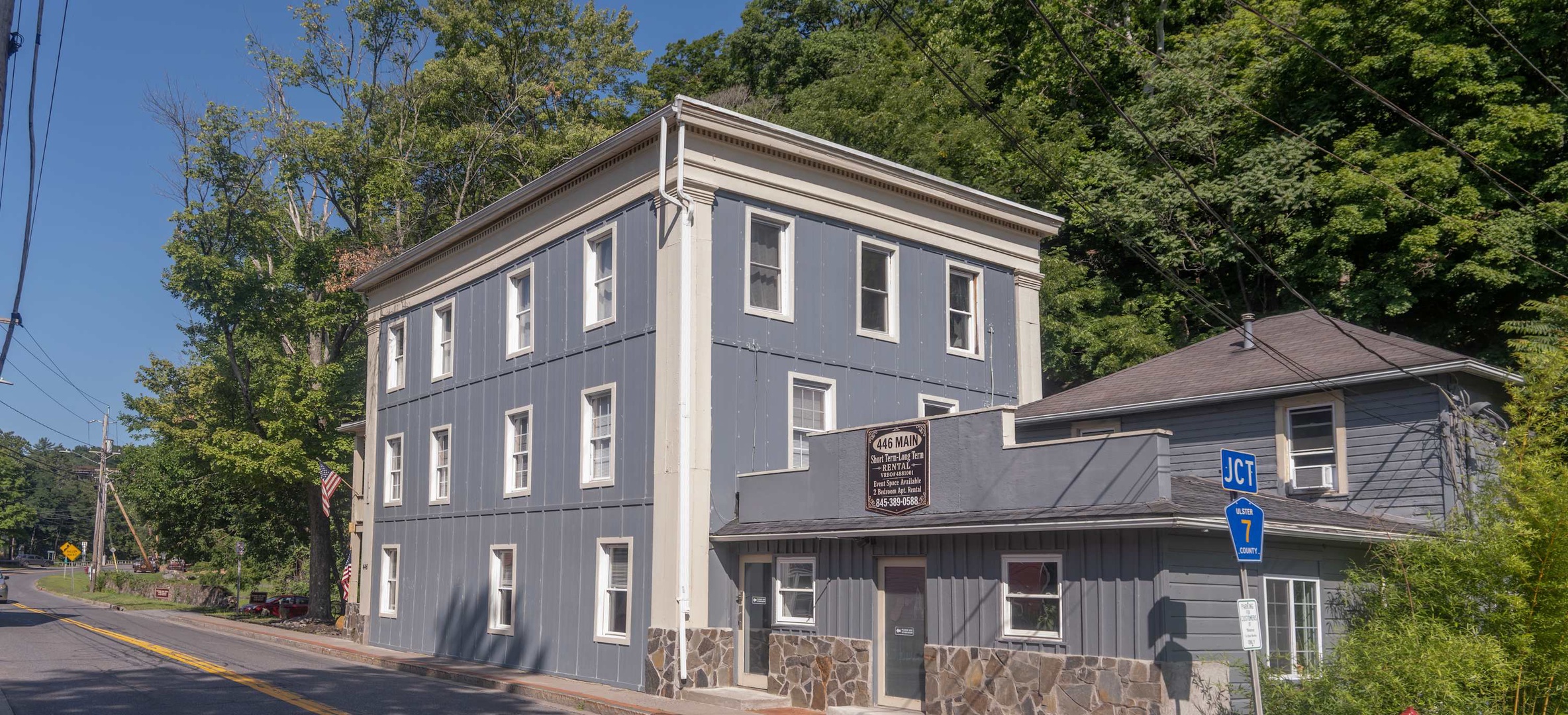 The Ames Building marks the entrance to this hillside property, nestled among lush trees and peaceful surroundings near Route 7, welcoming guests to a historic and scenic area.