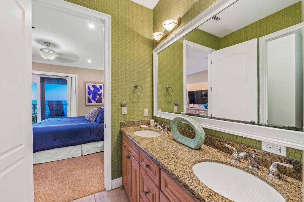 Your private bathroom features dual sinks with granite countertops, elegant green tile walls, and wood cabinetry—offering a bright, polished space to refresh and prepare for your day.