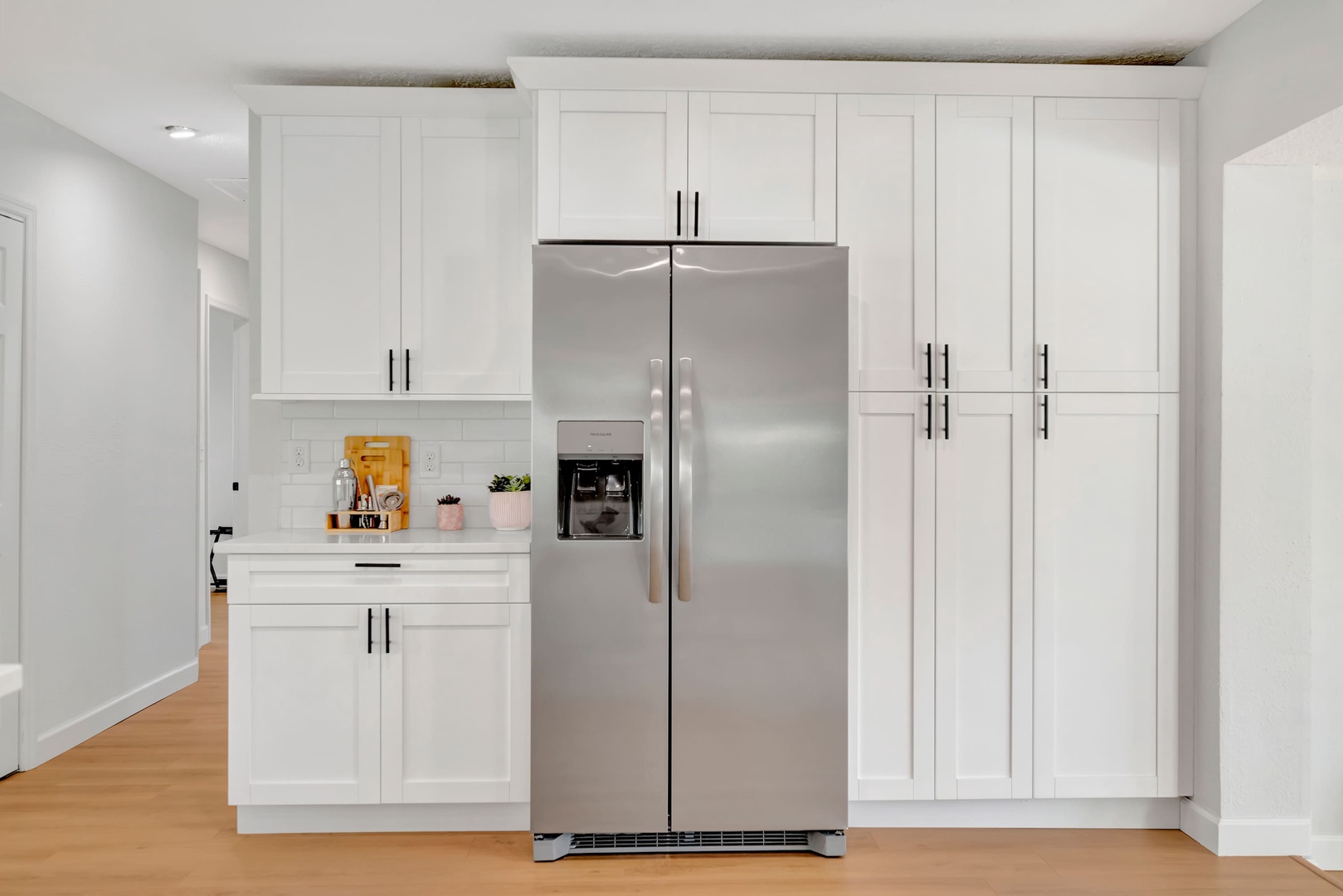Step into your modern kitchen with sleek white cabinetry and stainless steel appliances. Bright countertops and thoughtful touches like fresh plants and organized storage make cooking and gathering here a joy.