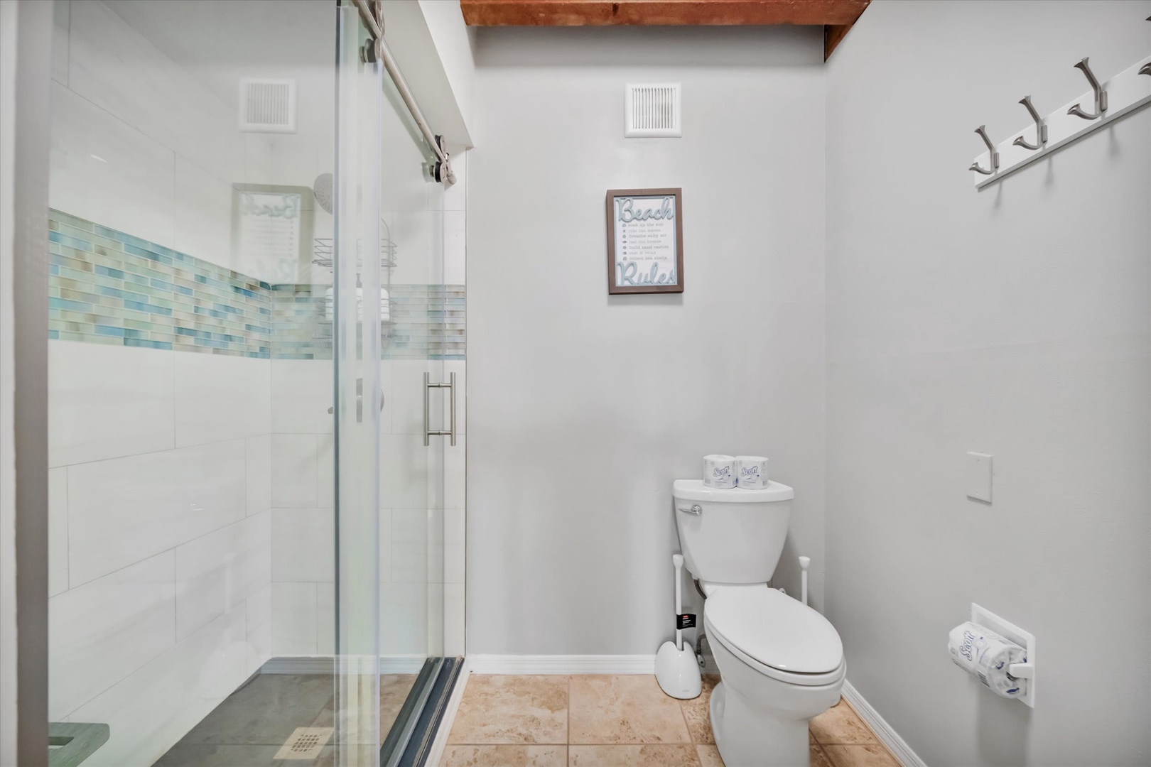 Refresh in your beautifully tiled bathroom with a spacious glass-enclosed shower and charming coastal accents throughout.