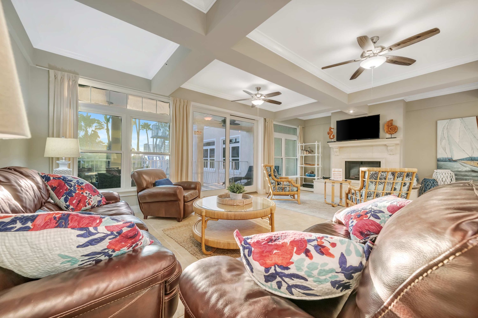 Sink into plush leather seating surrounded by bright natural light and coastal charm. Ceiling fans keep you cool while the fireplace adds warmth when needed—your perfect retreat for relaxation.