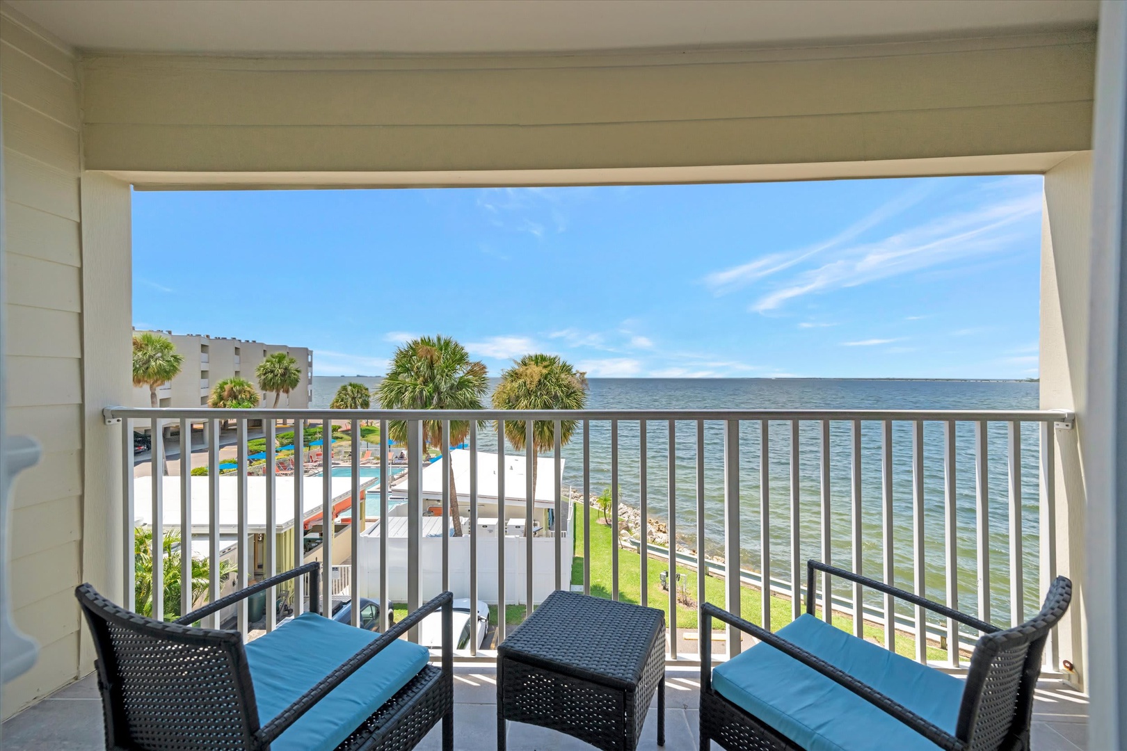 Your private balcony frames stunning waterfront views with comfortable seating to soak in coastal breezes and watch palm trees sway over tranquil turquoise waters.