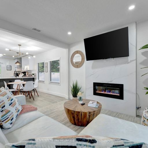 Bright, modern living space with natural light, plantation shutters, and a cozy fireplace. Perfect for relaxing evenings on the sofa or gathering around the nearby dining table.