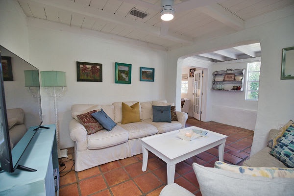 Step into your cozy living room, where soft white sofas invite you to sink in and unwind after a day of exploring. The warm terracotta tiles and bright open layout create a peaceful retreat that feels like home.