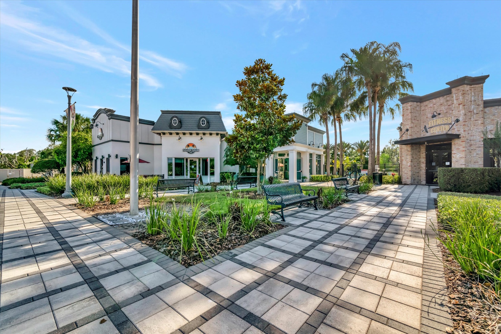 The property's landscaped grounds feature charming outdoor seating areas with benches, surrounded by palm trees and vibrant greenery. A peaceful setting to enjoy Florida's warm weather and sunshine.