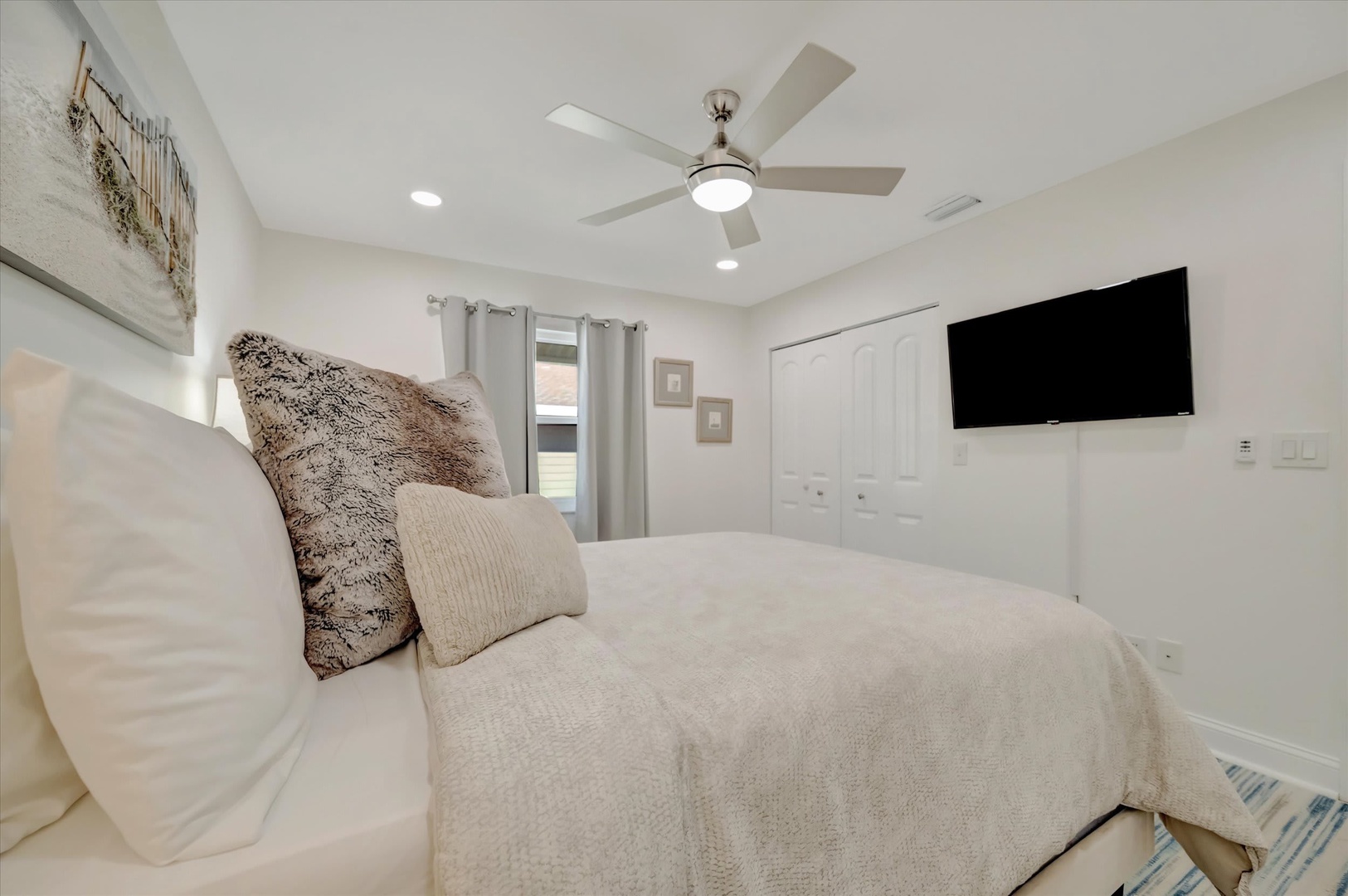 Sink into your plush bed surrounded by serene white tones and gentle textures. Your room stays perfectly comfortable with a modern ceiling fan overhead and a TV ready for movie nights.