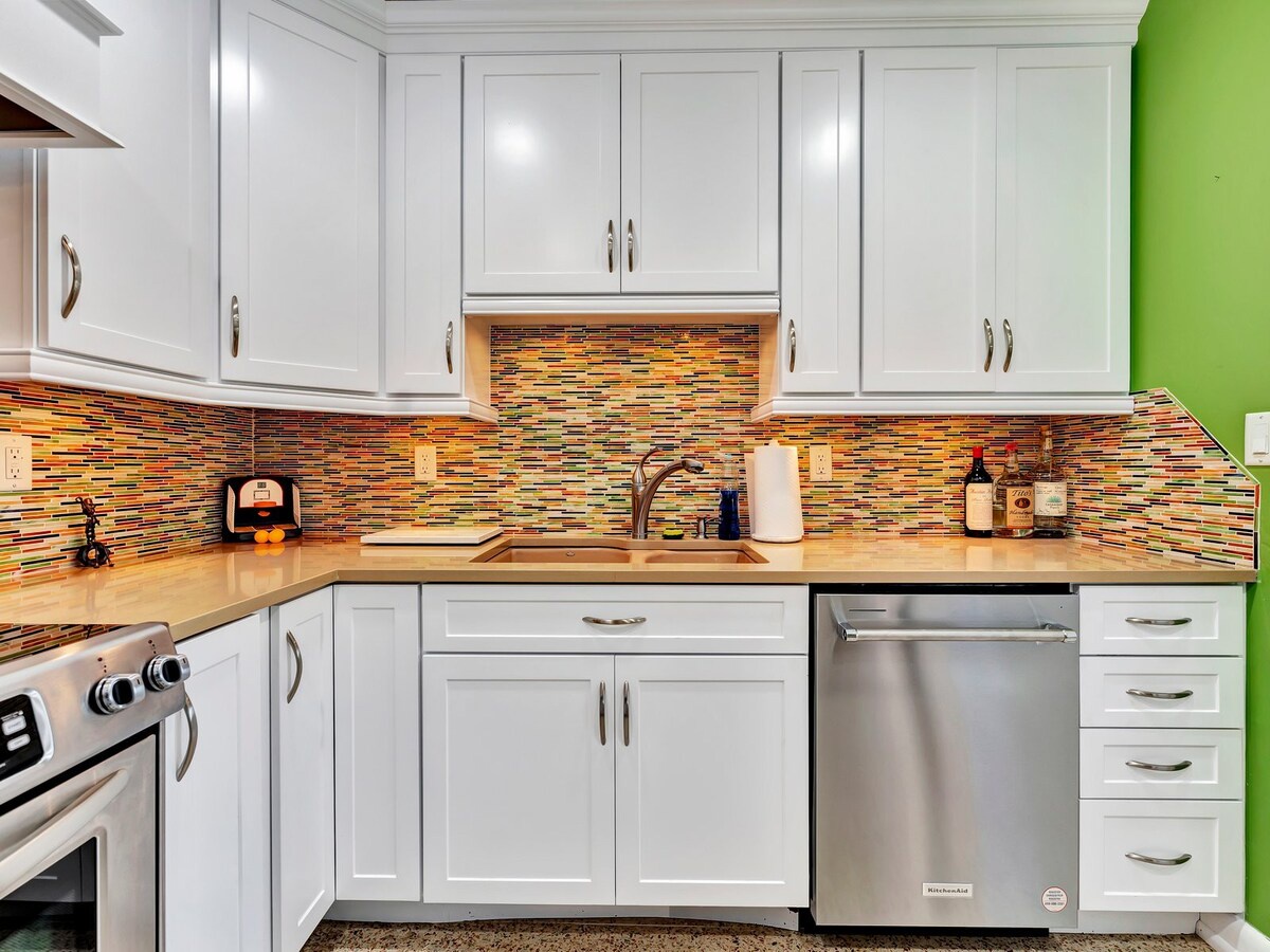 This bright, modern kitchen offers all the essentials for preparing your favorite meals, from the stainless steel dishwasher to the vibrant mosaic tile backsplash that adds warmth and personality to your space.