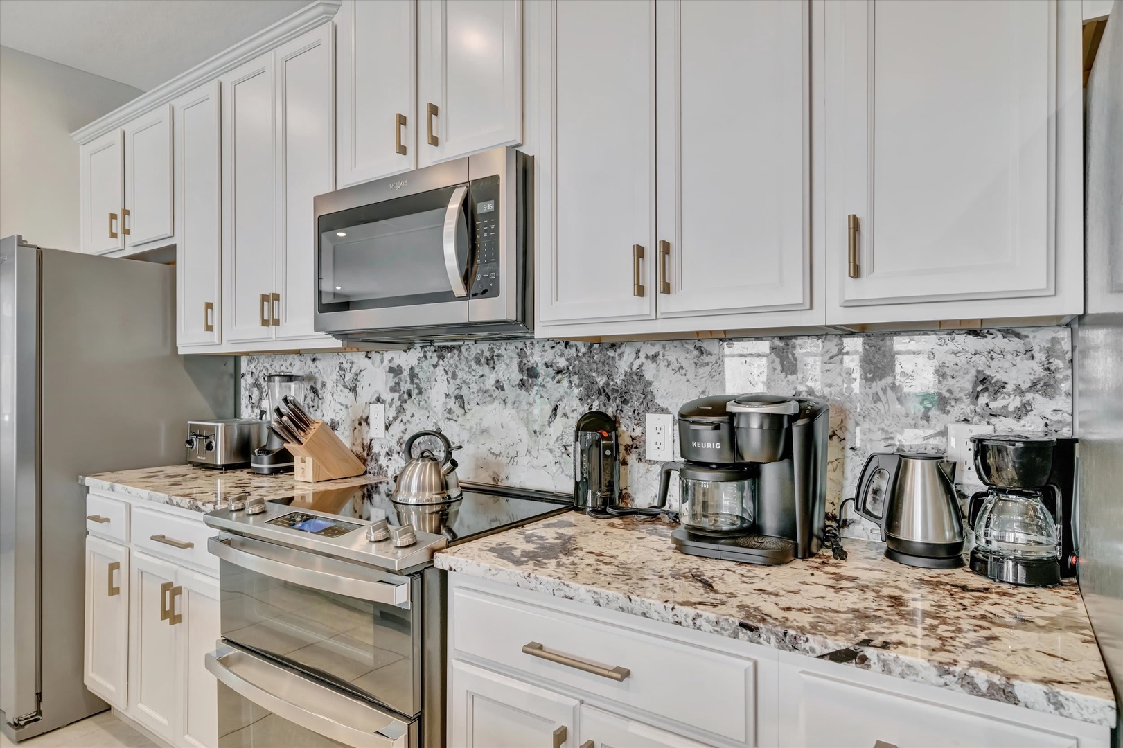 Your fully equipped kitchen awaits with gleaming granite counters, white cabinetry, and everything you need to prepare your morning coffee or a homemade meal during your stay.