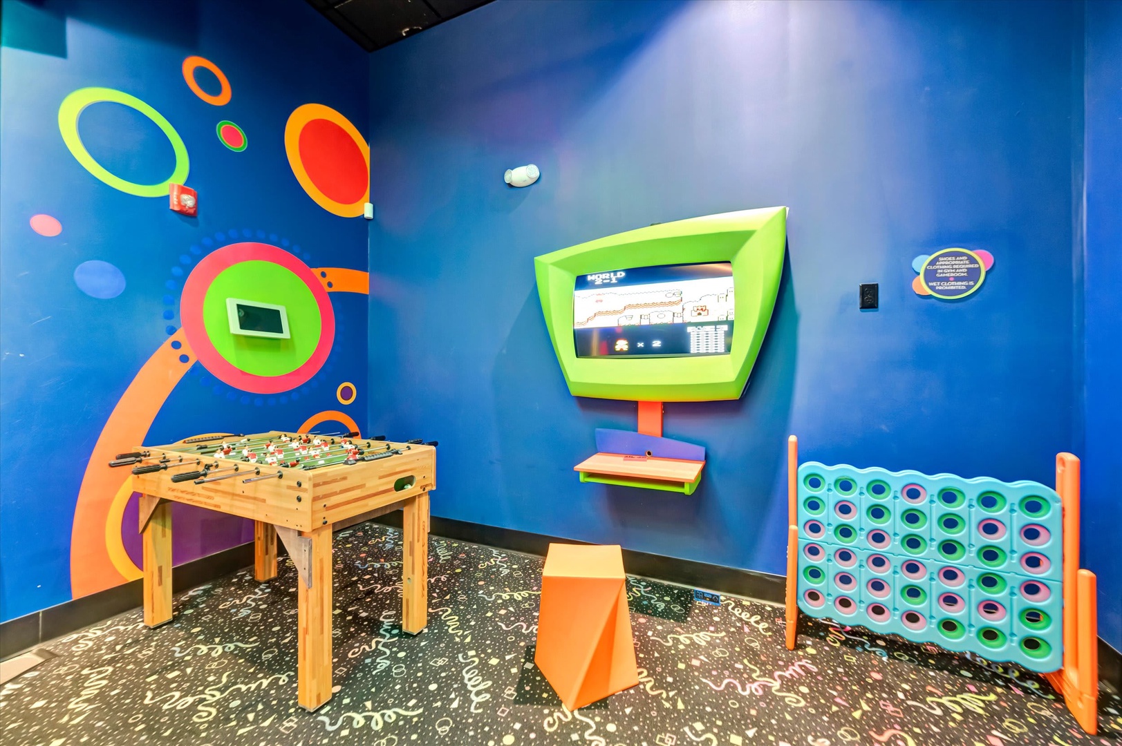 A colorful game room designed for young guests, complete with foosball, giant connect-four, and interactive wall games to keep everyone entertained.