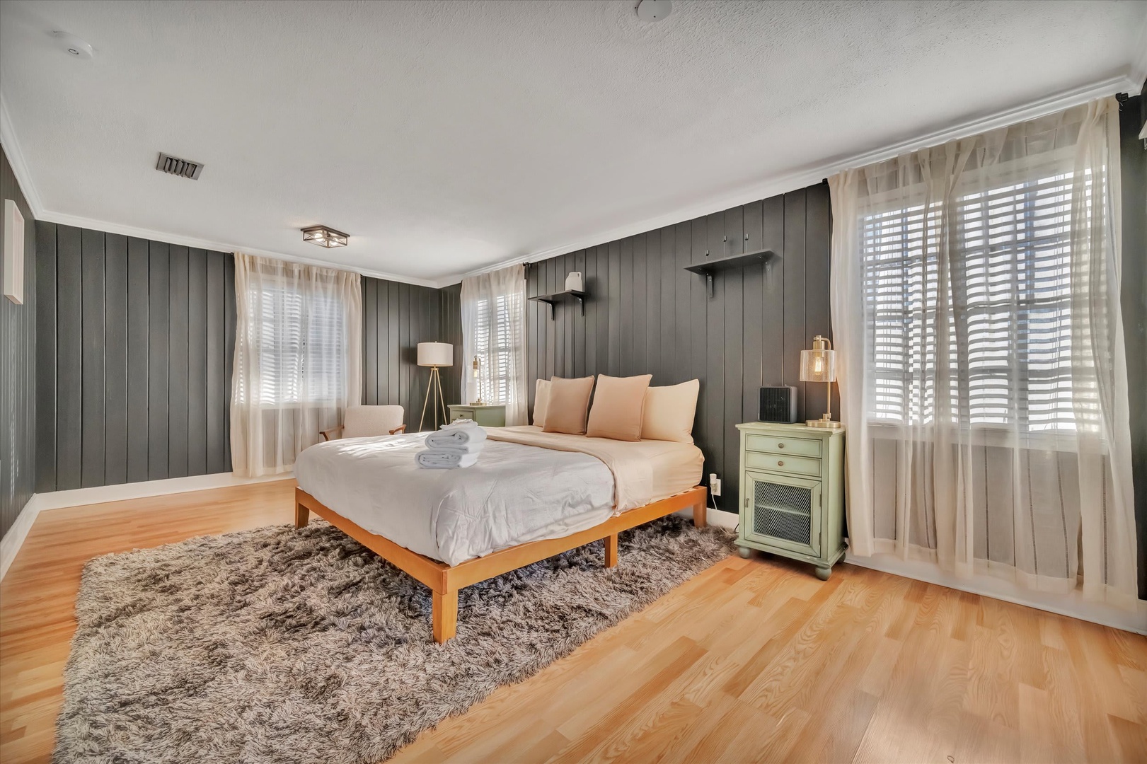 Step into your serene retreat, where warm hardwood floors meet soft textures and gentle natural light. The plush bed awaits, perfectly made with fresh towels ready for your arrival—everything designed for your ultimate comfort and relaxation.
