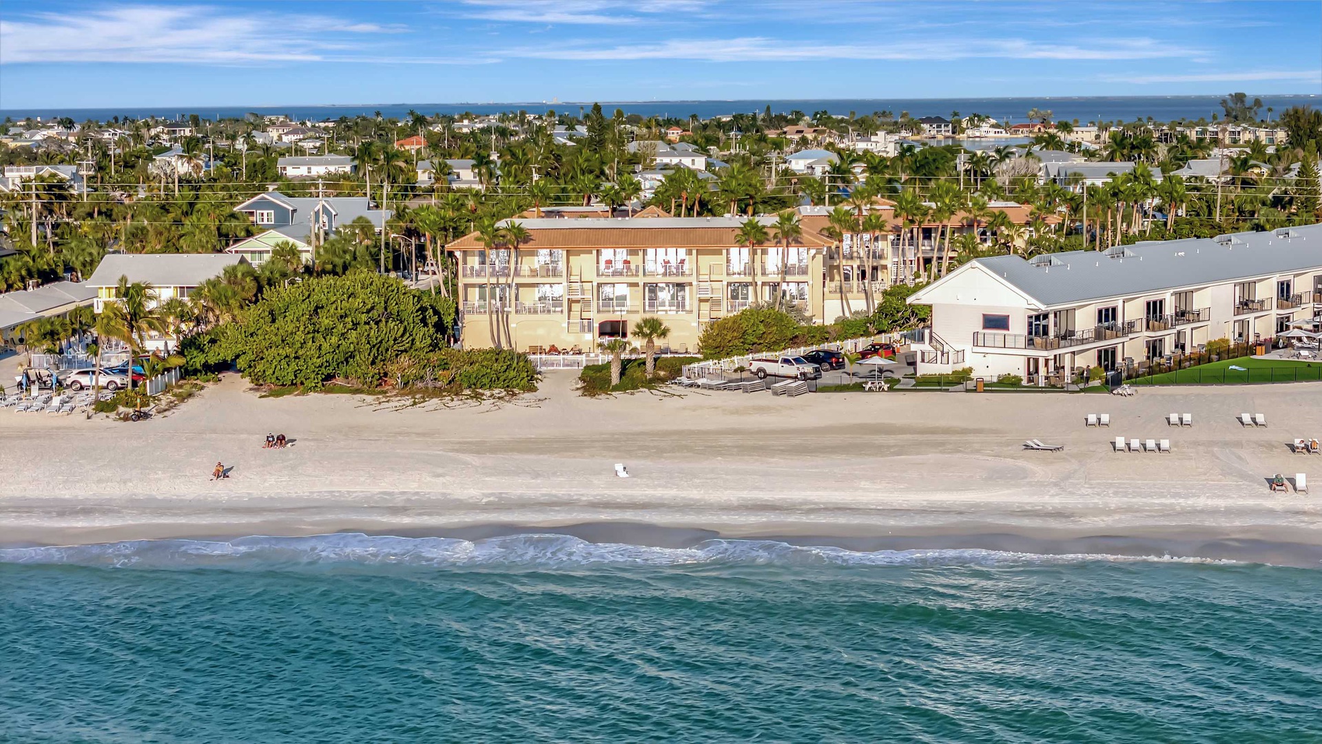 A beachfront property nestled along a pristine stretch of sand, surrounded by palm trees and coastal neighborhoods, with the ocean just steps away.