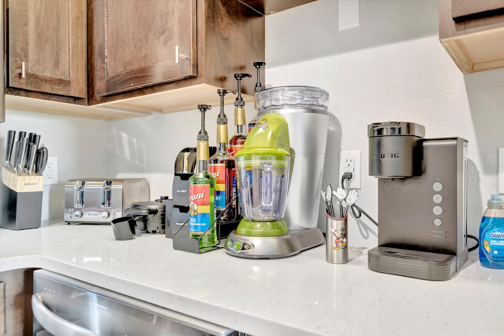 Your fully equipped kitchen awaits, stocked with everything you need to whip up refreshing drinks or quick meals—from the bright green blender to the toaster and espresso machine on spotless white counters.