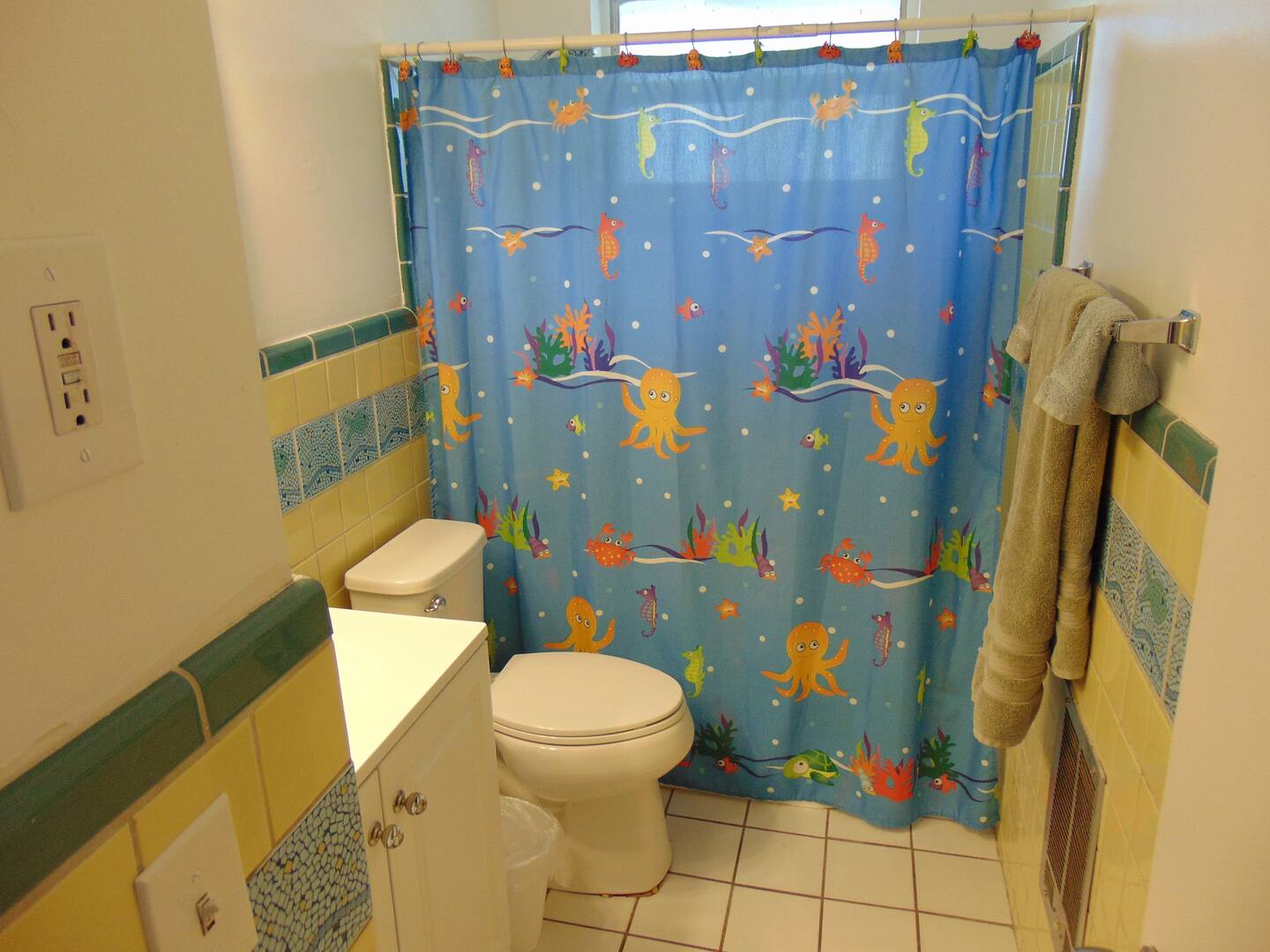 Bright and cheerful bathroom with colorful tile accents and playful ocean-themed shower curtain—perfect for families. Fresh towels are ready for your arrival.