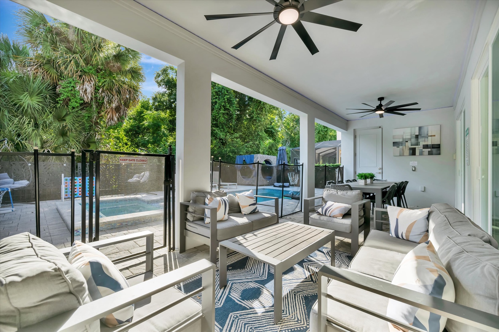 Your covered patio flows seamlessly into an open living space, where ceiling fans keep things breezy while you lounge or gather around the dining table, always just steps from the sparkling pool.
