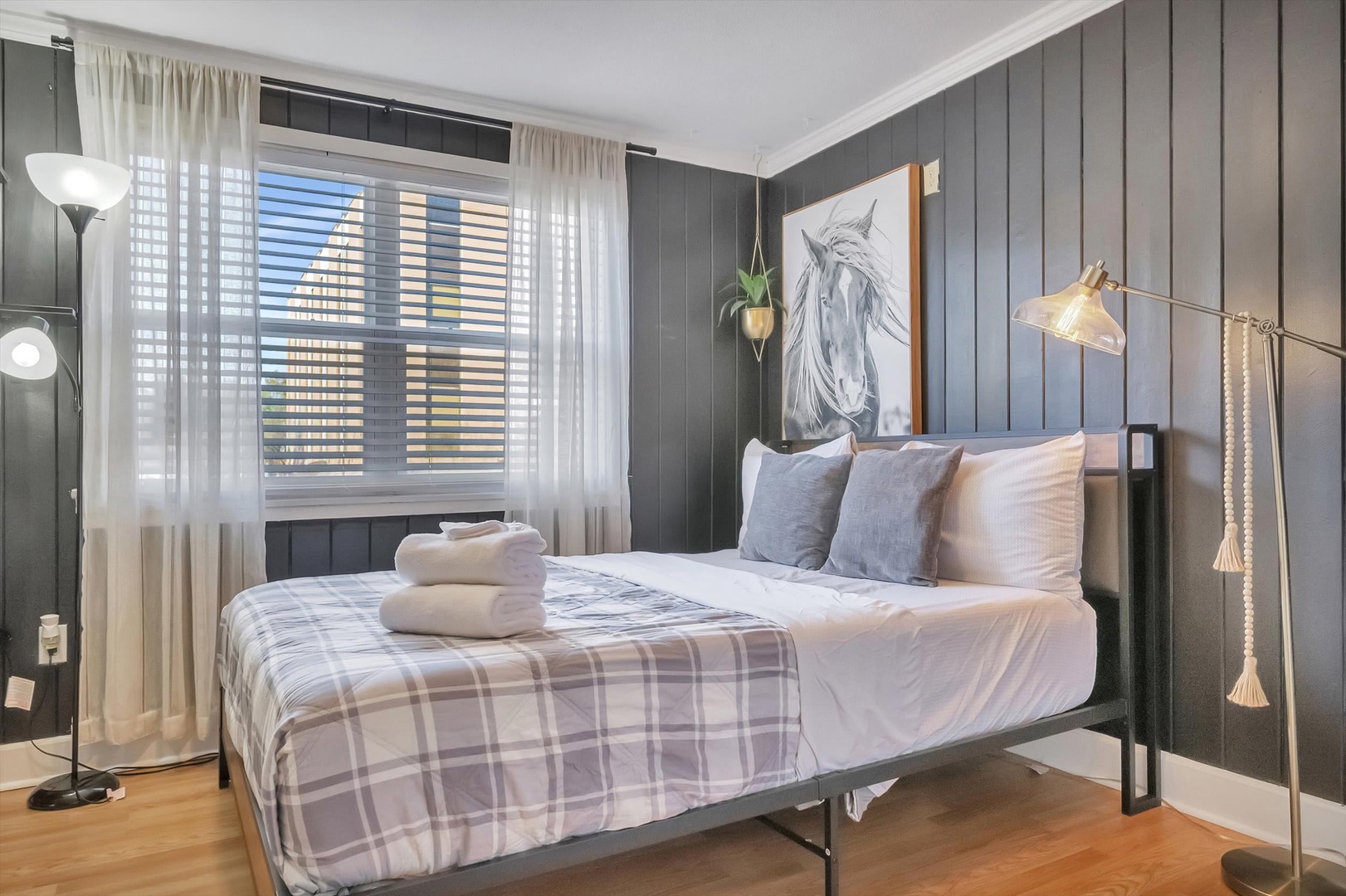 Sink into your luxurious bed beneath charcoal paneling and soft lighting. Fresh towels await, while natural light filters through gauzy curtains, creating your own peaceful retreat.