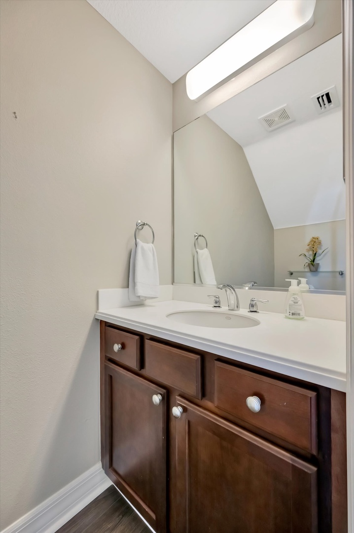 Your private bathroom features a polished vanity with clean lines and warm wood tones, creating a welcoming retreat after a long day.
