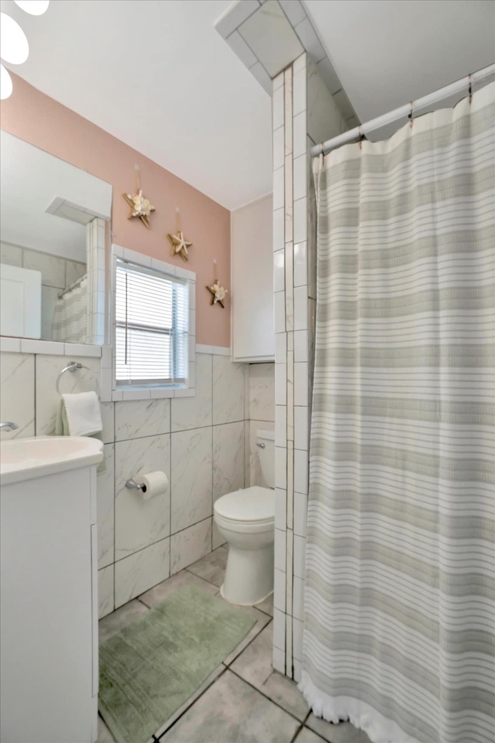 Step into your bright, well-appointed bathroom with coastal charm. Marble-look tile and soft color accents create a fresh, welcoming retreat after your beach adventures.