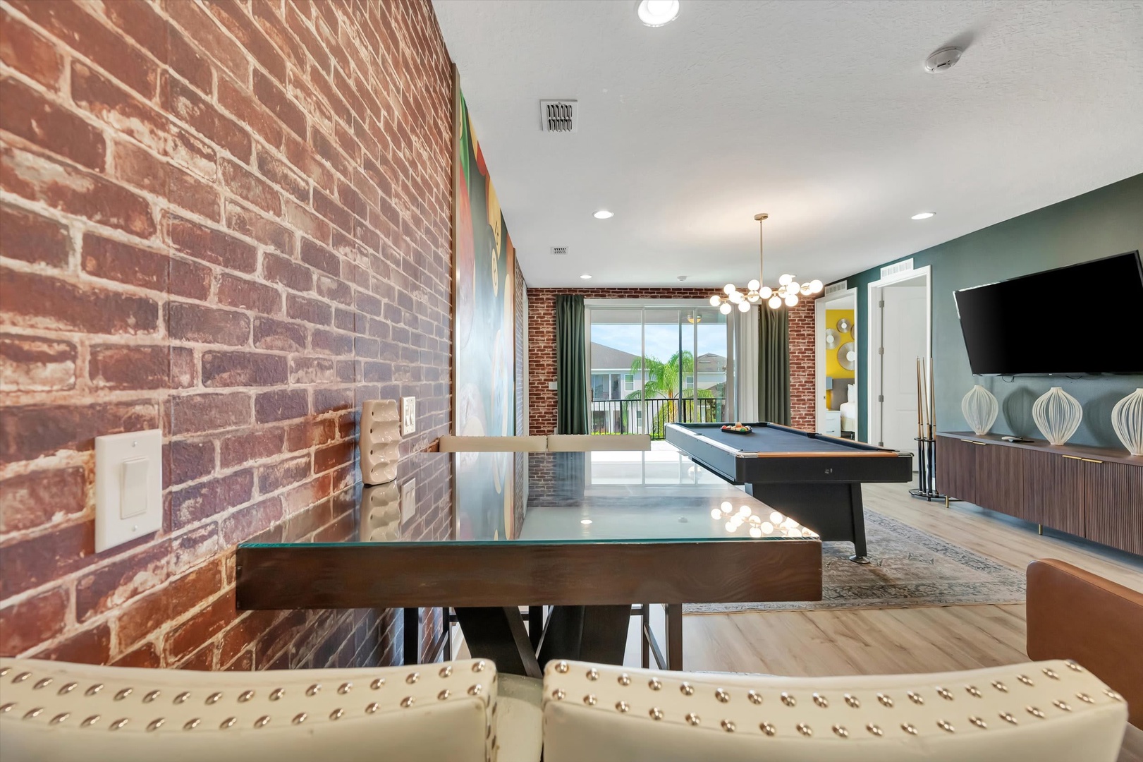 Gather around the sleek table for game night or unwind with billiards—exposed brick and contemporary touches create a stylish, social vibe for relaxing together.