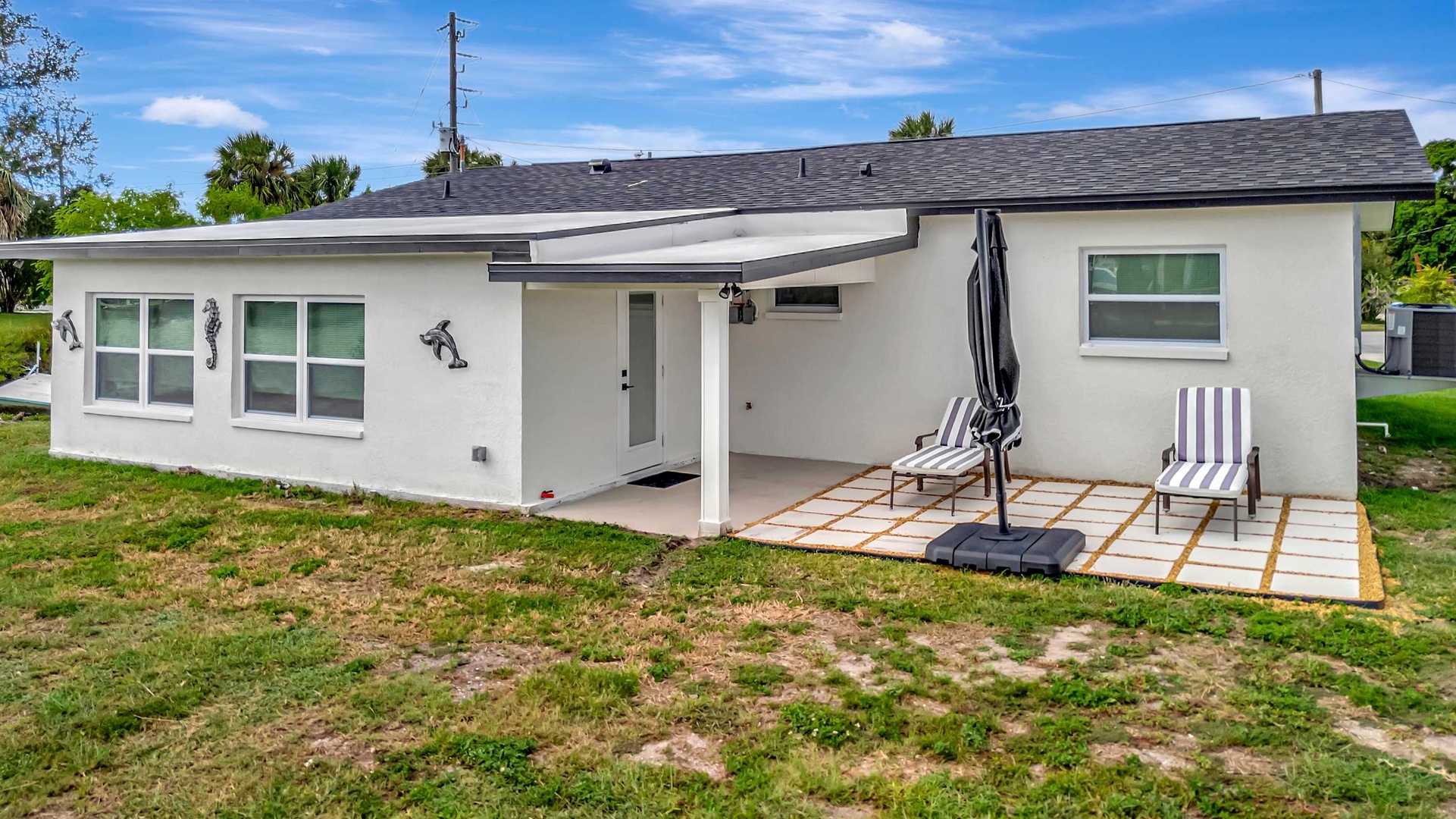 This charming coastal-style property features a covered patio with striped lounge chairs, perfect for sunny Florida afternoons. The beachside decor and outdoor relaxation space set the tone for a memorable getaway.