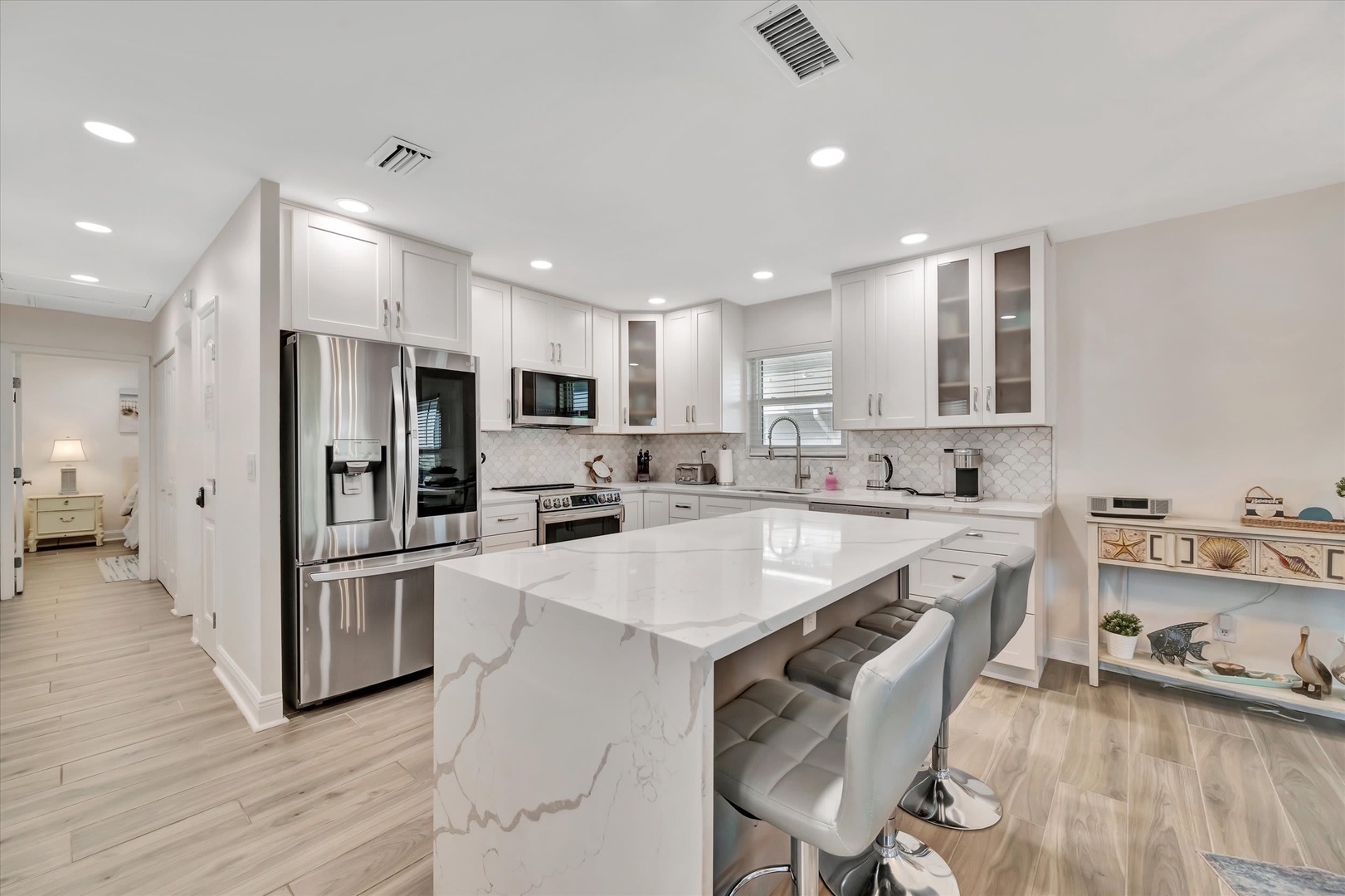 Your home away from home features a stunning gourmet kitchen with gleaming marble-look countertops, stainless steel appliances, and a spacious island with bar seating—perfect for gathering over morning coffee or preparing your favorite meals.