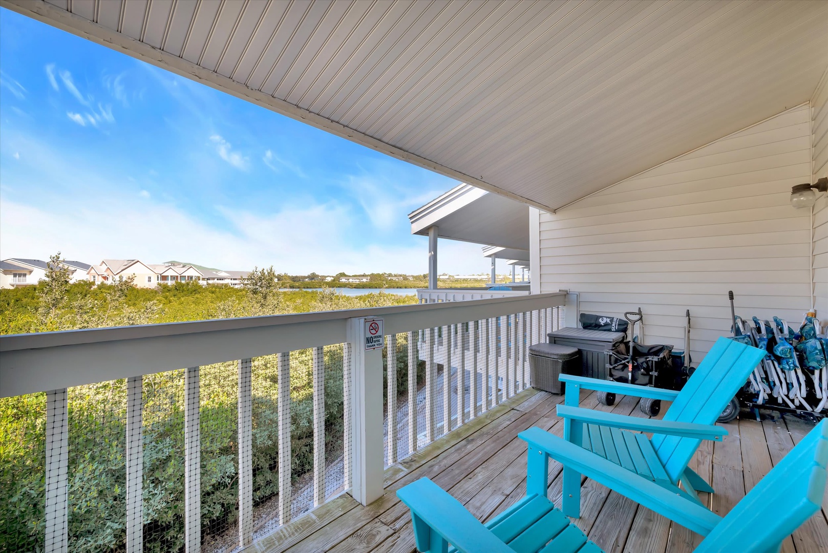 This covered balcony offers your perfect spot to relax in turquoise Adirondack chairs while taking in coastal dune views, with a private hot tub nearby for unwinding after beach days.