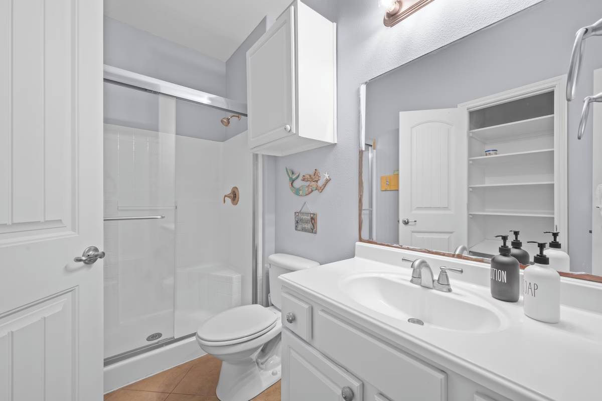 Step into this bright, coastal-inspired bathroom where crisp white cabinetry and fresh linens await. The walk-in shower and well-lit vanity make your morning routine feel effortless.