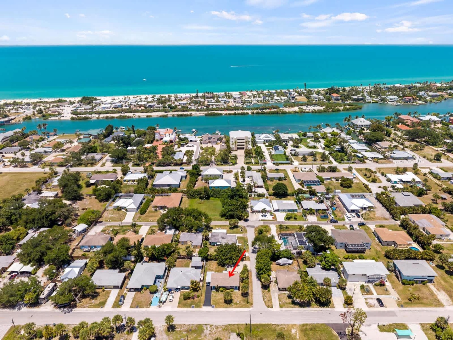 Aerial view of a coastal neighborhood with turquoise Gulf waters, sandy beaches, and waterfront canals—the property sits within this vibrant beachside community.