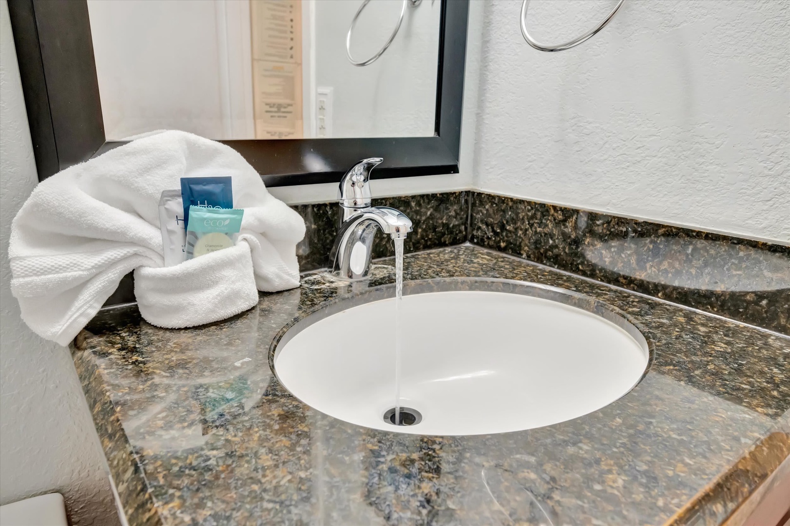 Freshen up in your elegantly appointed bathroom, featuring a polished granite vanity, crisp white linens, and premium amenities ready for your arrival.