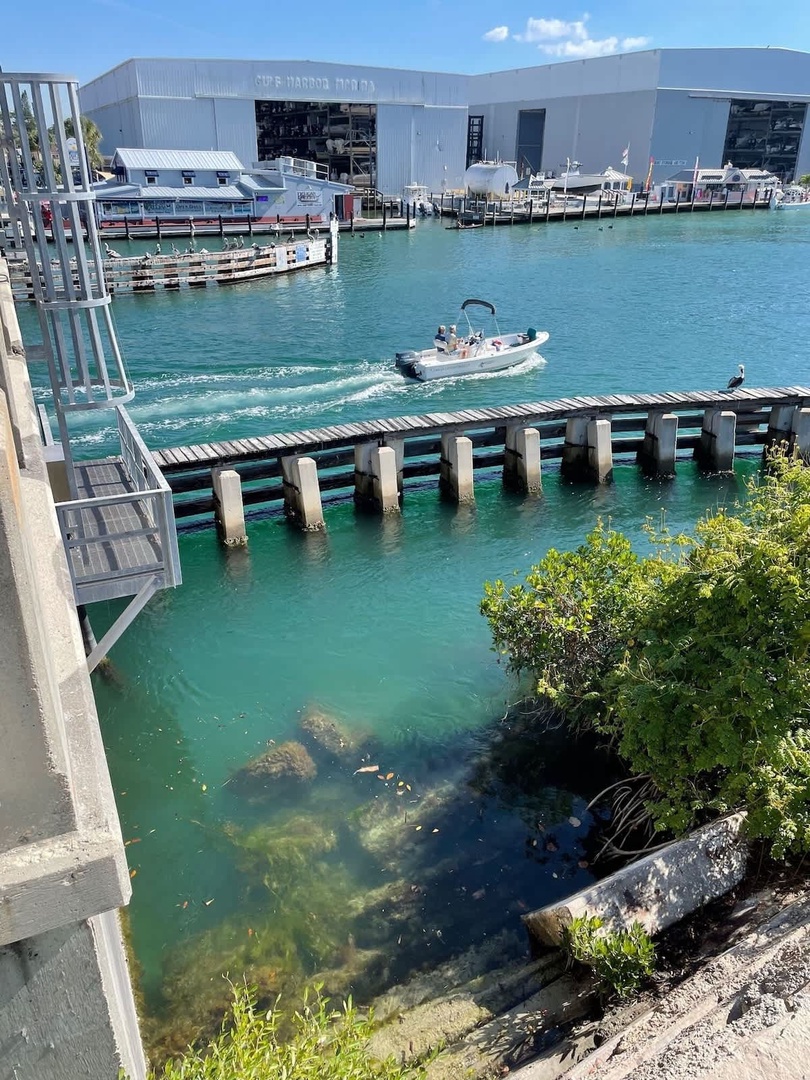 Coastal marina area with clear turquoise waters, boat docks, and waterfront structures nearby.