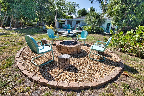 Gather around the fire pit for evening conversations under the stars, with comfortable seating for your group surrounded by lush tropical landscaping and views of the charming cottage.