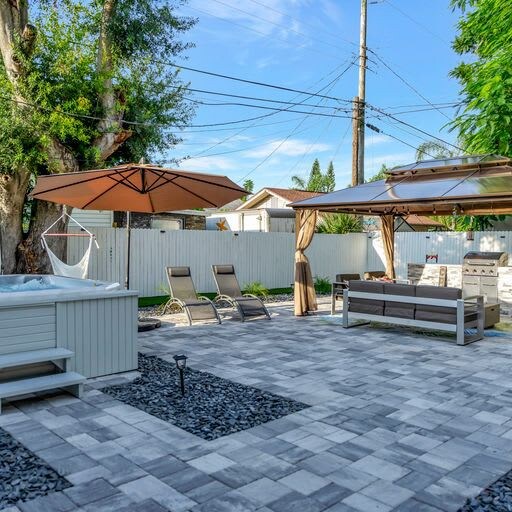 Your private backyard oasis awaits with a sparkling hot tub, shaded lounge seating, and a BBQ area perfect for gathering under the California sun—all yours to enjoy.