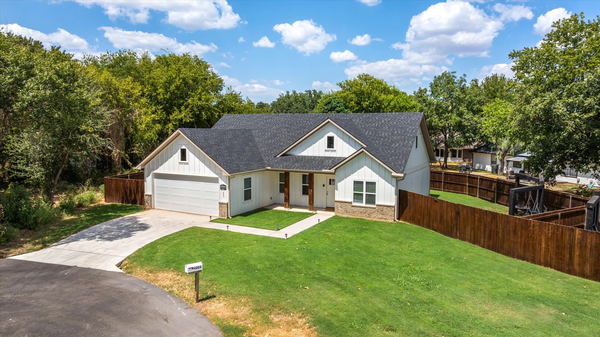 A charming single-story home nestled among mature trees, featuring a spacious lawn and private fenced yard—perfect for a peaceful escape surrounded by natural beauty.