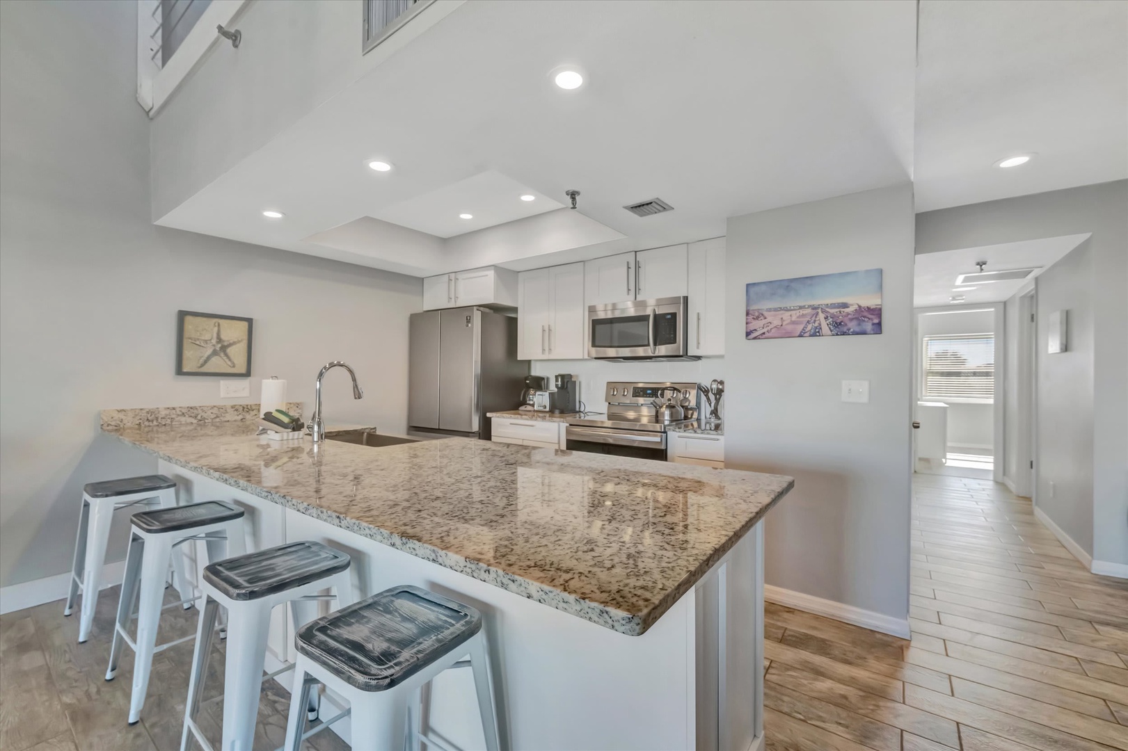 Step into your bright coastal kitchen featuring granite countertops, stainless steel appliances, and a breakfast bar with seating for four—perfect for morning coffee and vacation meal prep.