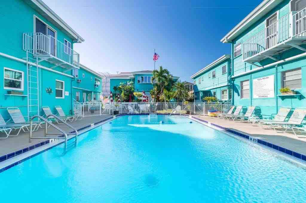 Enjoy the refreshing pool surrounded by vibrant coastal architecture and swaying palms — your perfect sunny retreat awaits.