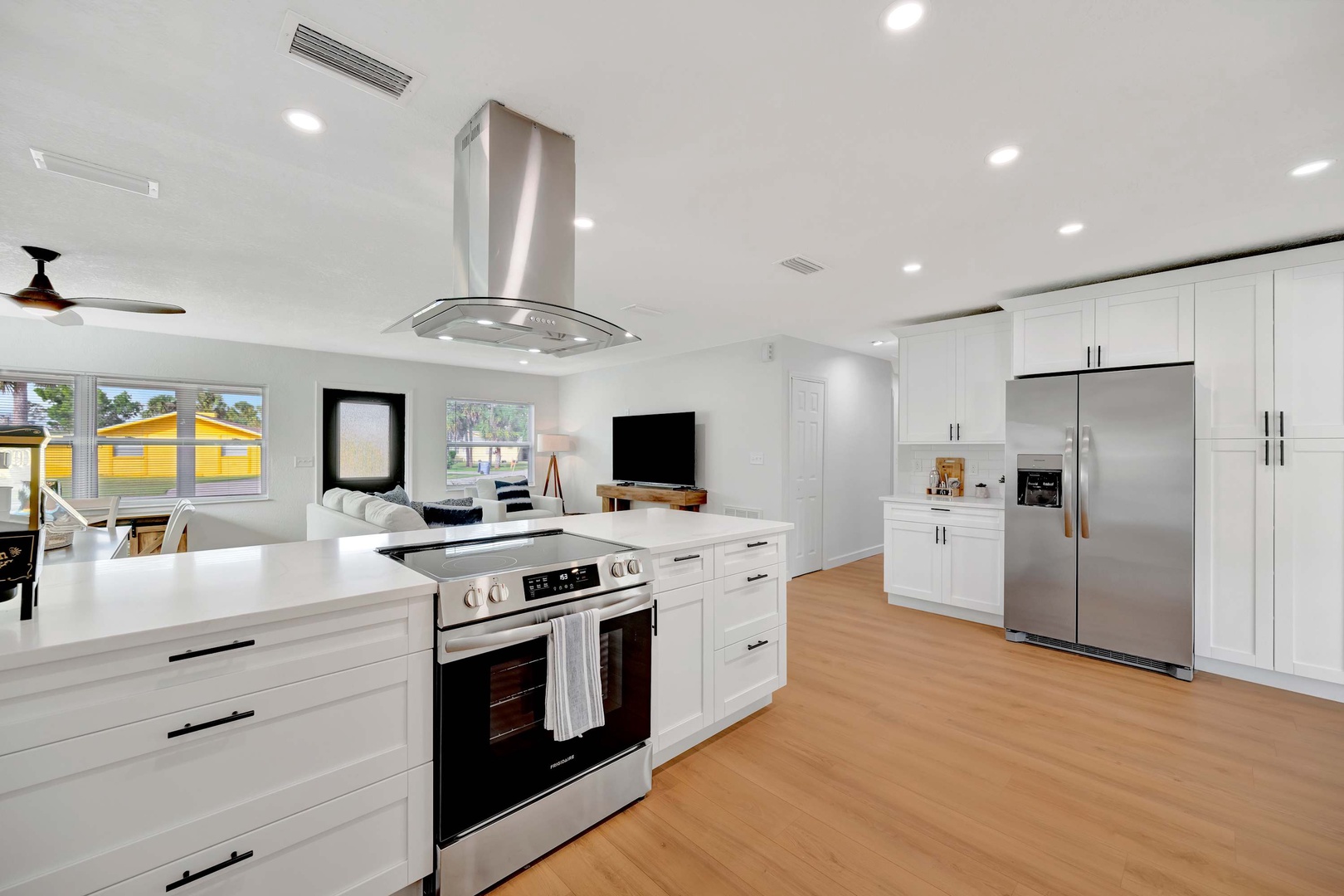 Step into your bright open kitchen where gleaming white cabinetry and modern stainless appliances create an inviting space to gather and cook, with sunlit views connecting you to the world outside.