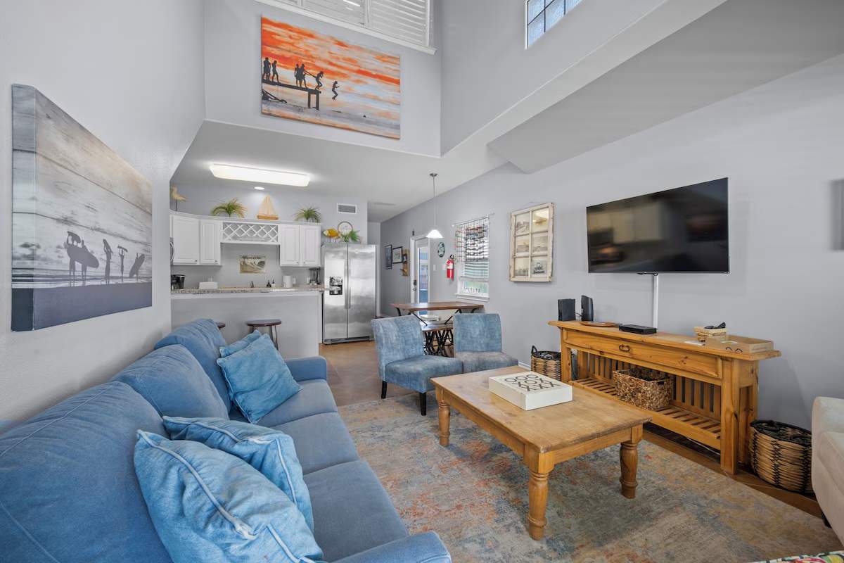 Gather in this bright, open living space where soaring ceilings and coastal light invite you to relax. Plush seating and a well-equipped kitchen create your perfect home base for beach getaways.