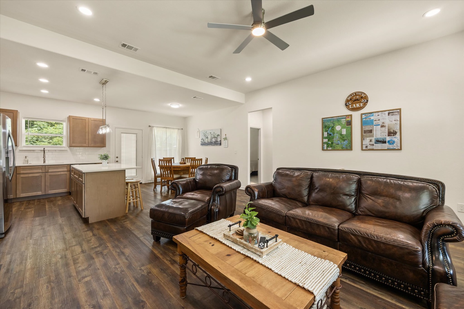 Relax in the open-plan living space with rich leather seating, rustic accents, and a fully equipped kitchen. Abundant natural light and a ceiling fan create an inviting, breezy atmosphere perfect for unwinding.