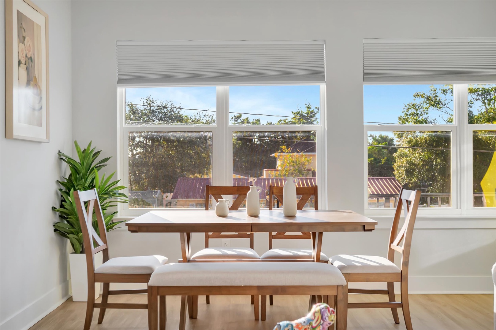 Gather around this sun-drenched dining table, where natural light pours through large windows framing charming street views of the neighborhood's rooftops and greenery.