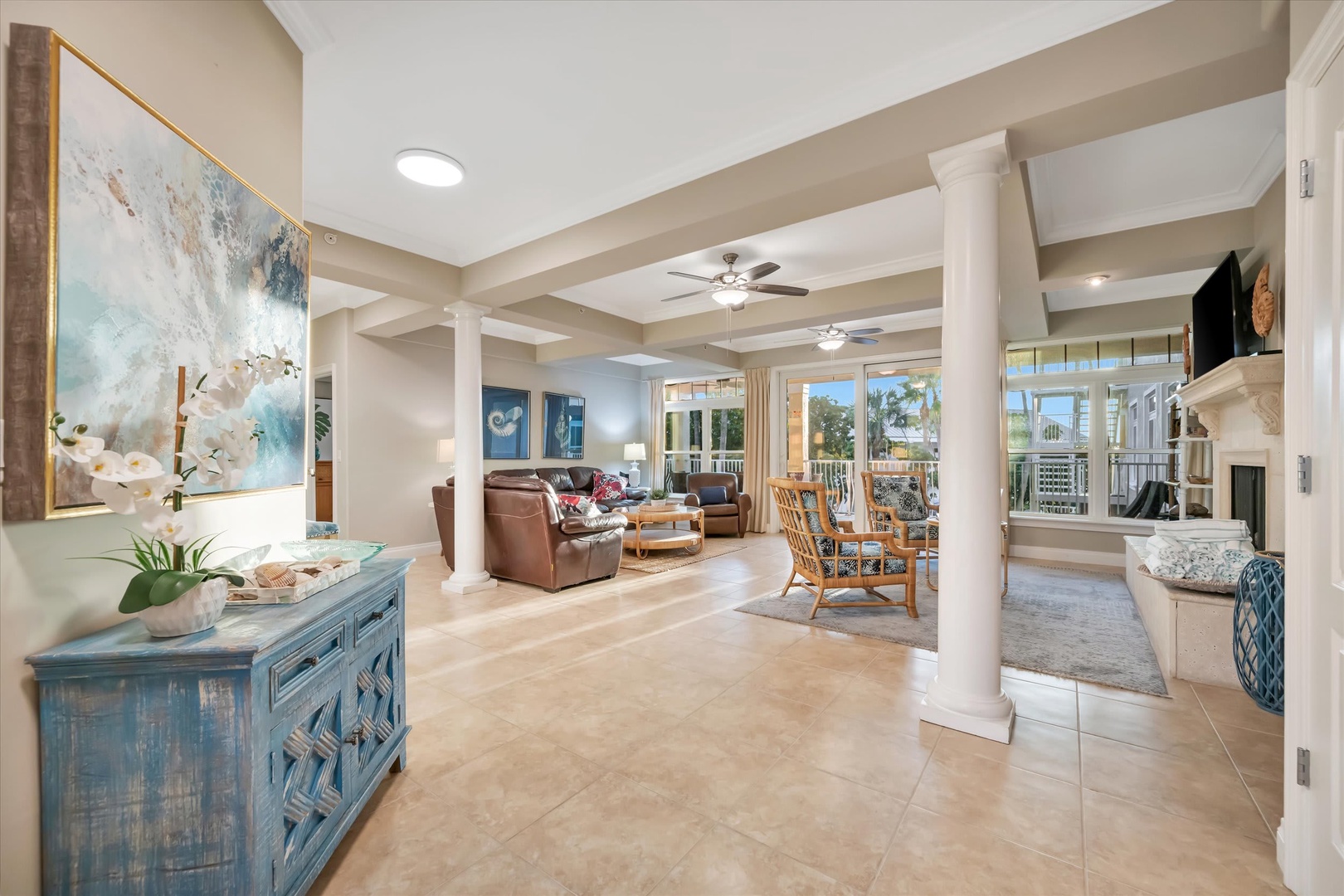 Step into your bright, open living space where coastal elegance meets comfort. Relax in the inviting seating areas or gather around the dining table, all while palm trees sway just beyond your windows.