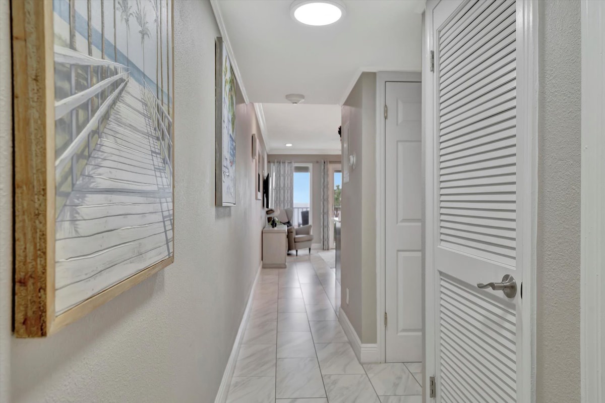 Step inside to find a bright, welcoming hallway that flows seamlessly toward your comfortable living space, with coastal-inspired art setting a relaxed vacation tone from the moment you arrive.